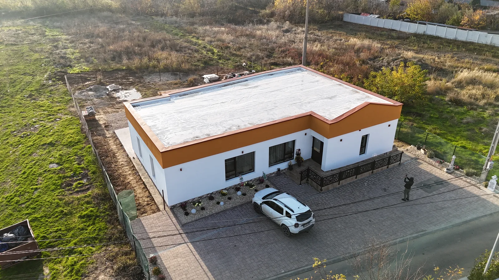 Aceeași clădire terminată, cu fațada albă și portocalie, văzută din dronă
