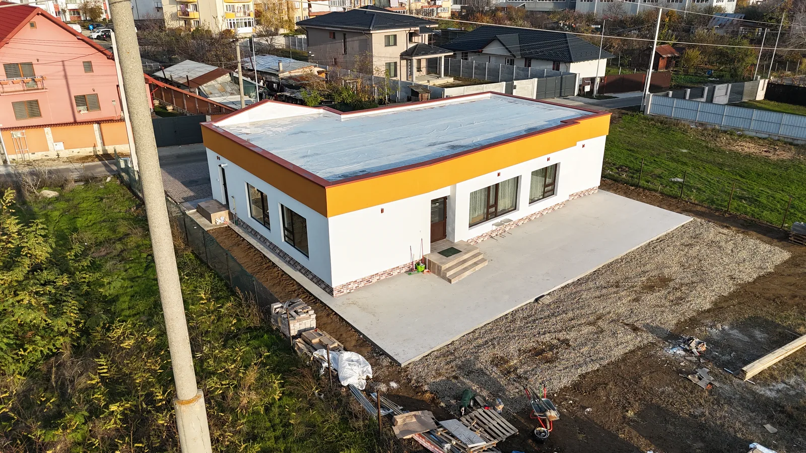 Clădire de tip afterschool, terminată, cu fațadă albă și portocalie, văzută din dronă