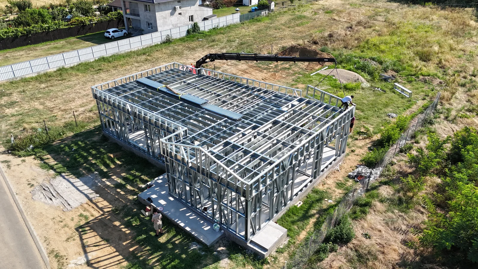 Structura metalică a unei clădiri de tip afterschool, montată și încă neînchisă, văzută din dronă