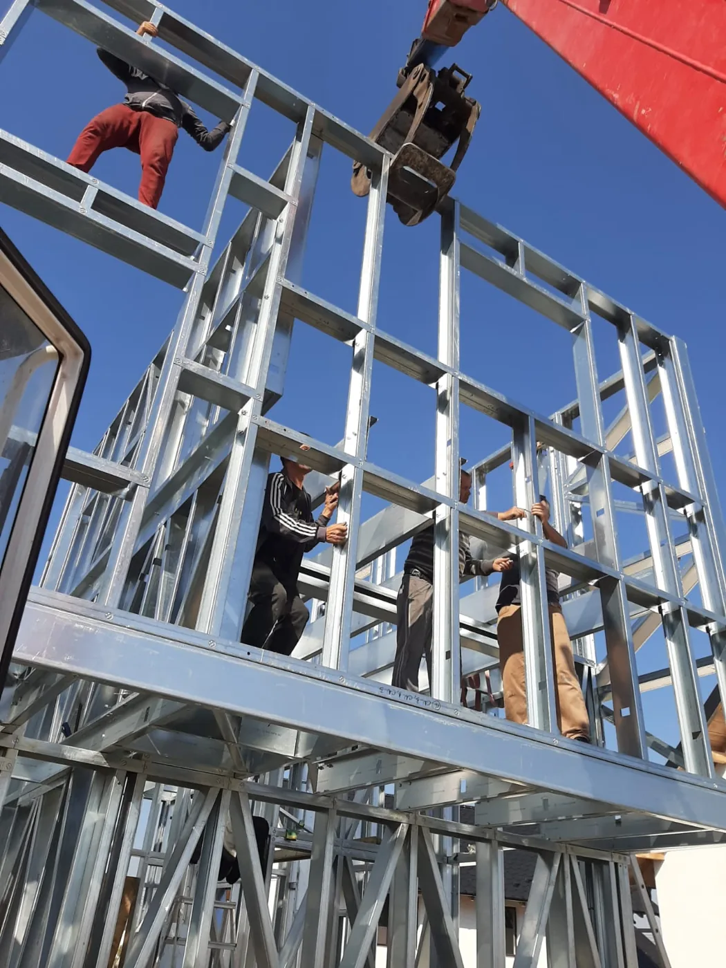 Echipa de montaj pe structura unei case, cu macaraua deasupra